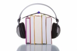 A képen egy könyveket ábrázoló ábra látható, felettük pedig egy mp3 lejátszó és egy fejhallgató