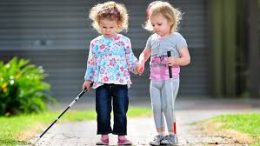 A képen 2 vak kislány sétál