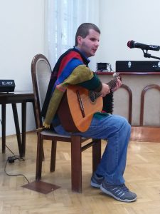 A képen Domoszlai János látható gitározás és éneklés közben