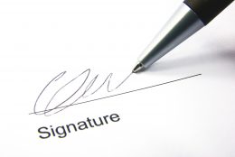 A képen egy toll látható, amint valaki aláírja vele a nevét