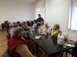 A körzeti megbízott beszél az újpesti klub tagjainak, akik egy asztalnál ülve hallgatják őt